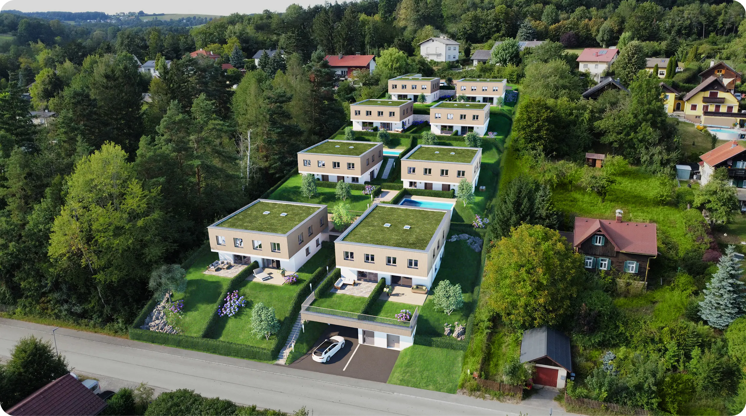 Luftaufnahme der Neubausiedlung mit modernen Häusern und begrünten Flachdächern an einem bewaldeten Hang.